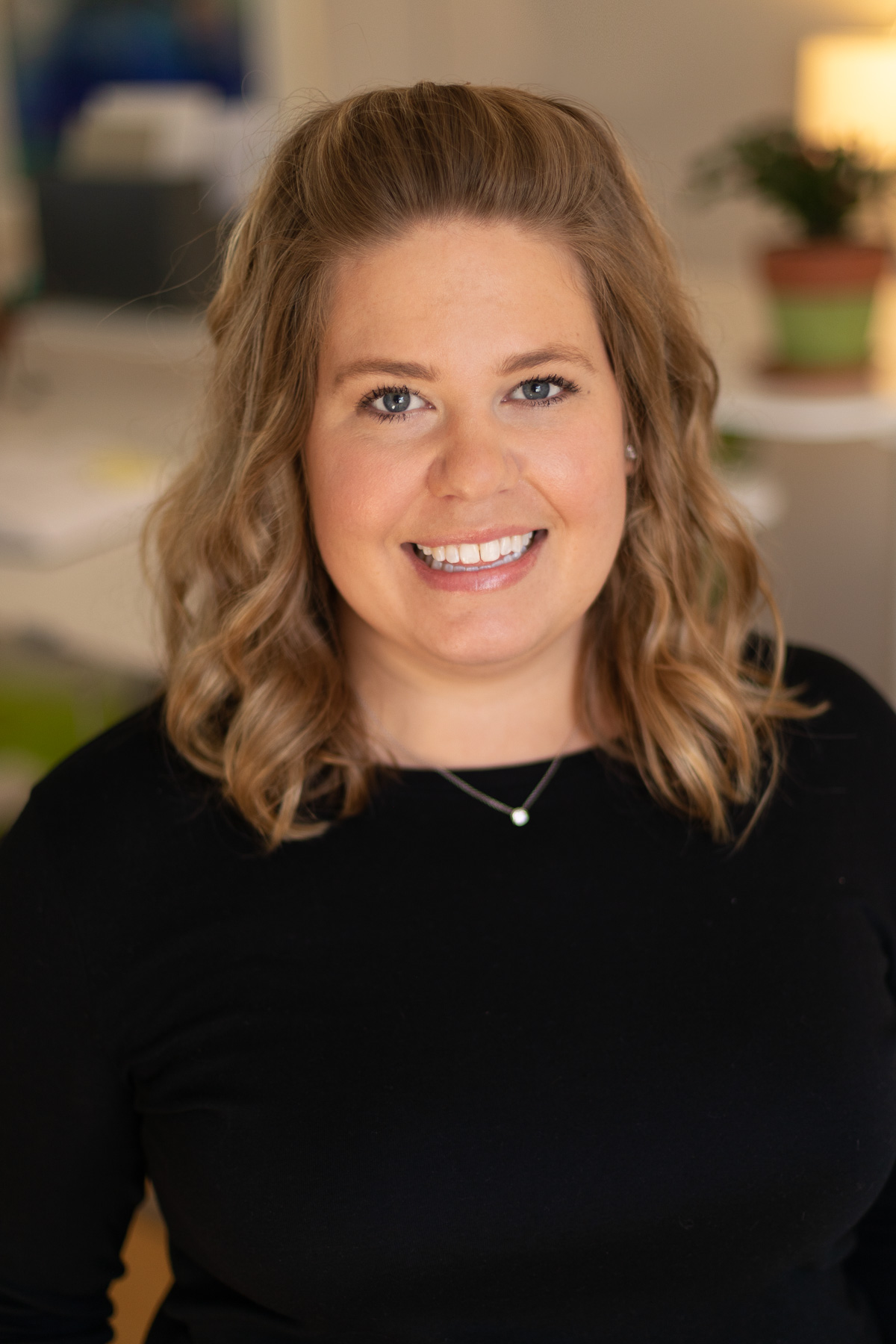 A young female professional project manager at Circuit Media, smiling and wearing a delicate necklace and black shirt