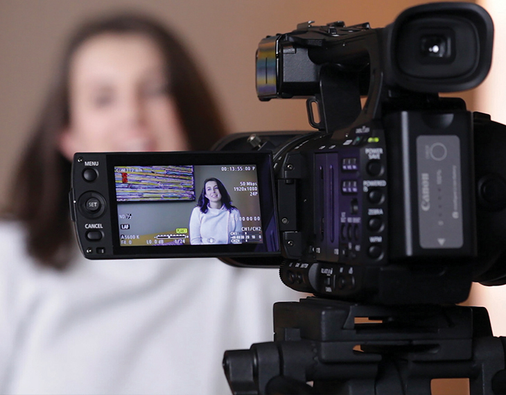 a woman smiling while being filmed