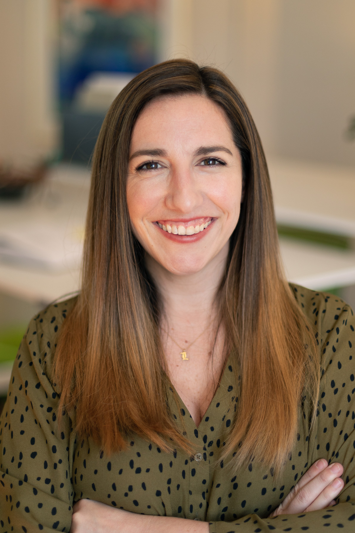 A young female professional project manager at Circuit Media, smiling and wearing a green button up shirt with black dots