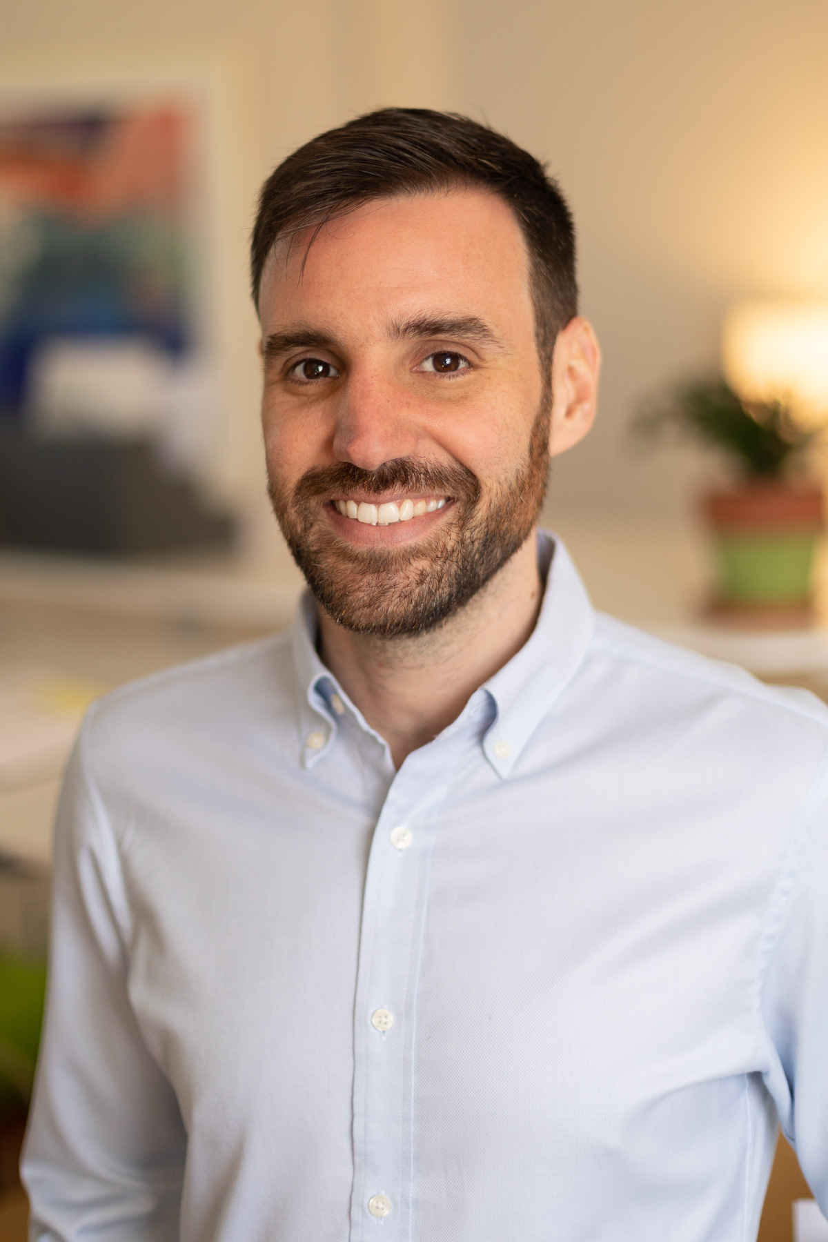 A young male professional editor at Circuit Media, smiling and wearing a light blue collard button up